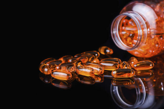 A bottle of orange pills with dark background shows that orange is one of the most visible colors for human eyes.