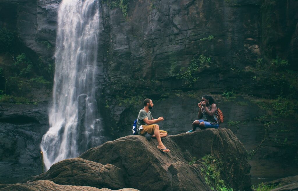 a girl and a boy talking by a waterfall