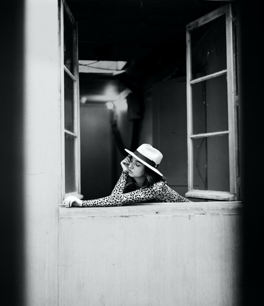 a girl in a white hat outside the window