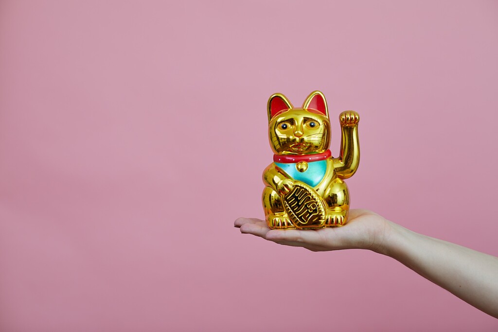 yellow cat sculpture on a girl's hand on a pink background