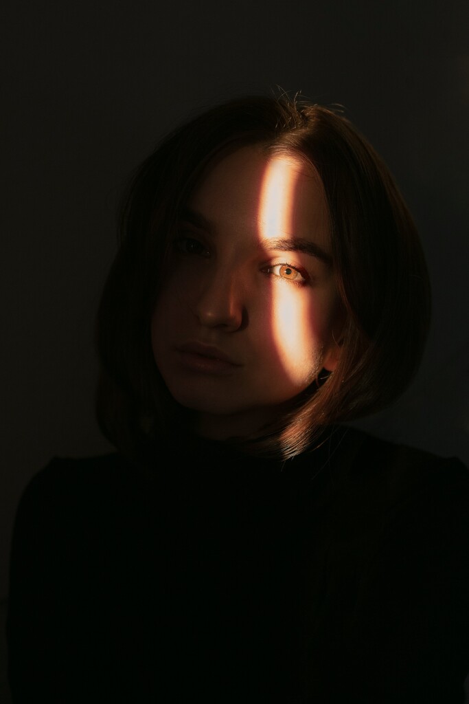 monochrome image of a girl standing in front of the light and the light has taken part of her face