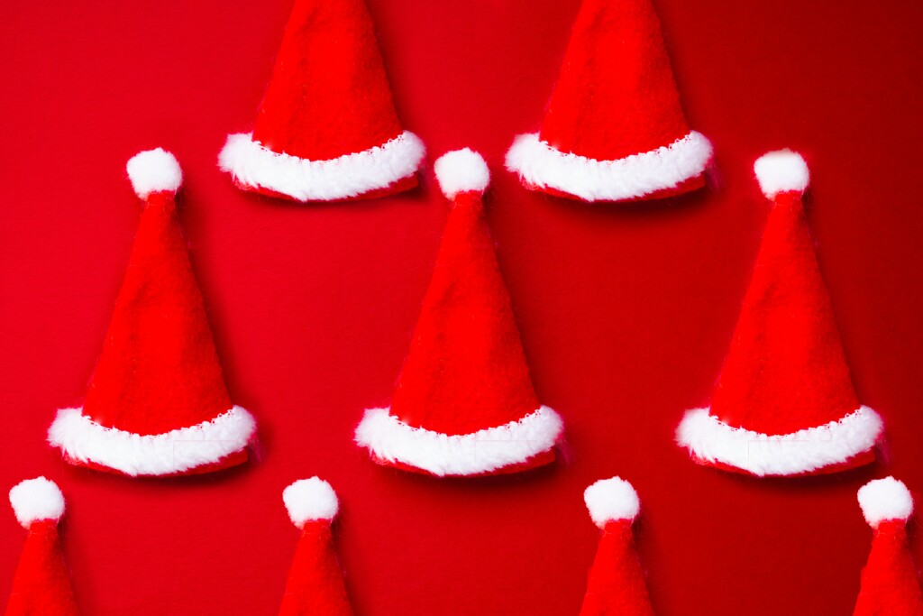 Picture of red Santa hats on red background
