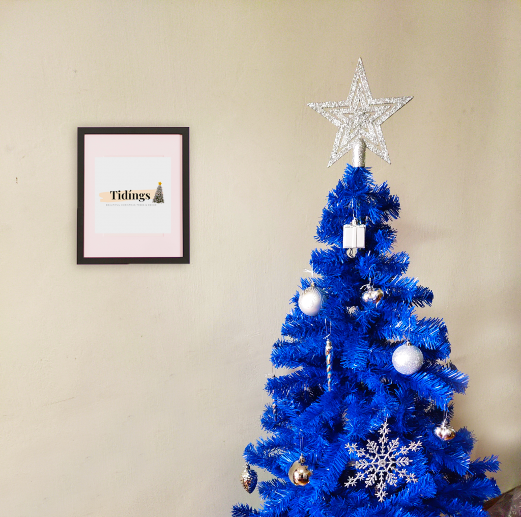 Blue Christmas tree with a large silver star topper on top of the tree and silver pendants.
