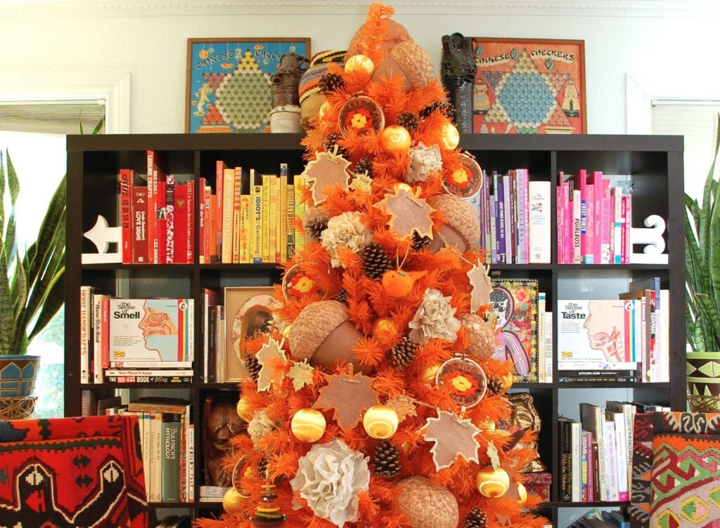 Orange Christmas tree with autumn theme, plantain leaf pendants, pine fruit, oak, white paper flowers and white and orange plastic balls.
