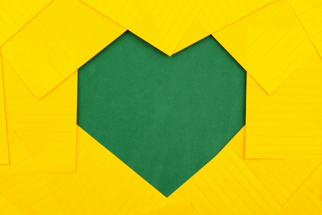 Dummy image made of yellow paper sheets on a green background made of green color heart paper sheets.