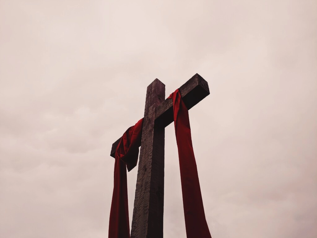 an image of a wooden cross sunk into the ground covered with red velvet cloth.