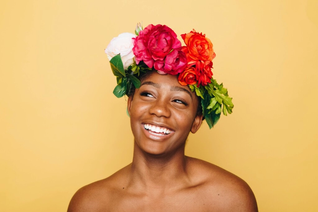 A picture of a girl of color smiling and a crown of flowers on her head.