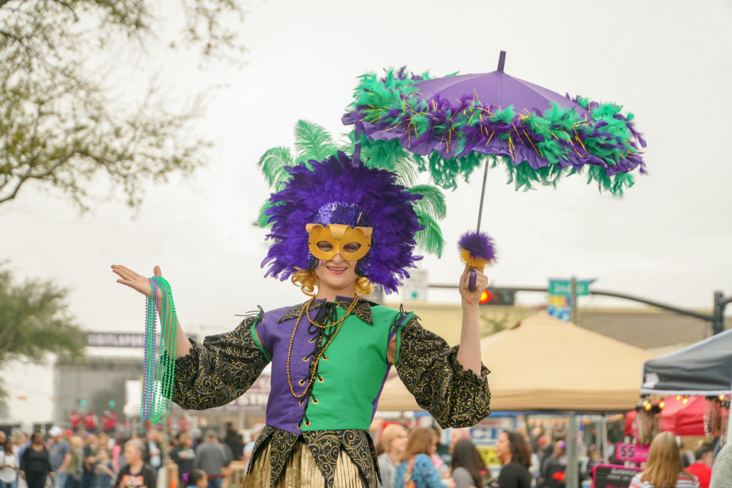 a picture of a woman in a purple and green dress and a golden mask at Mardi Gras
