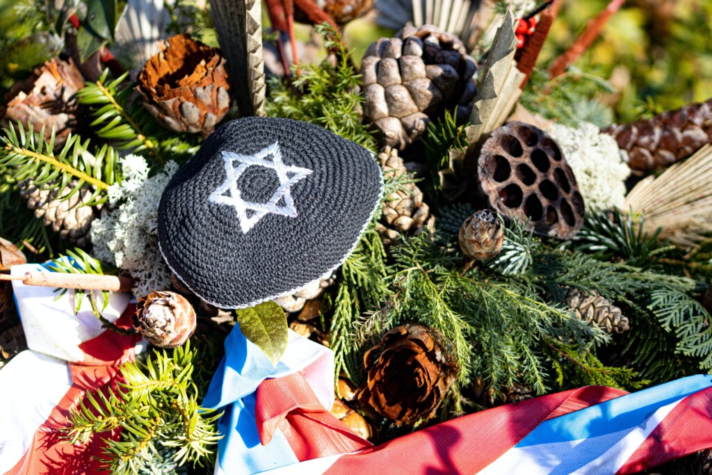 an image of a woven hat with the symbol of Judaism next to bouquets and colored flags