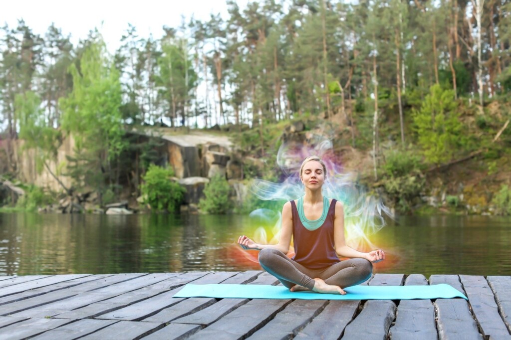 a picture of a girl that doing yoga with colored aura around her